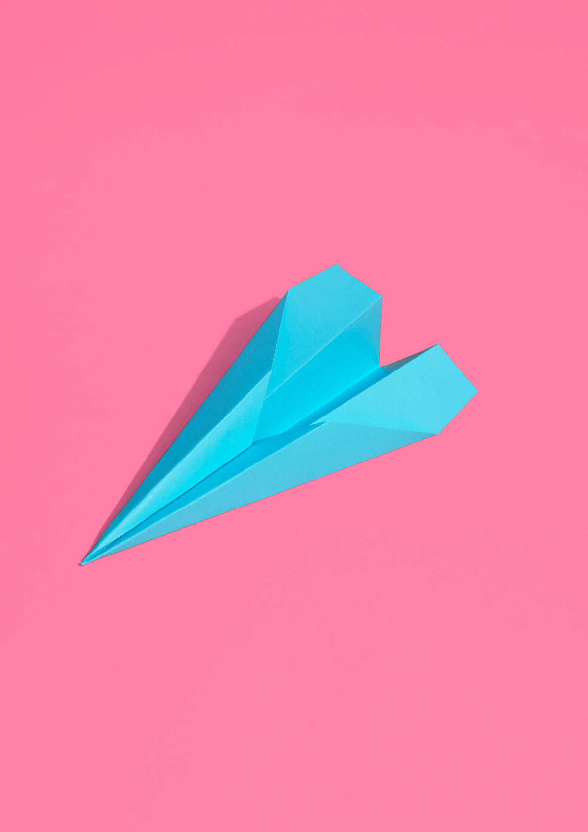 Mint green paper plane on a pink background