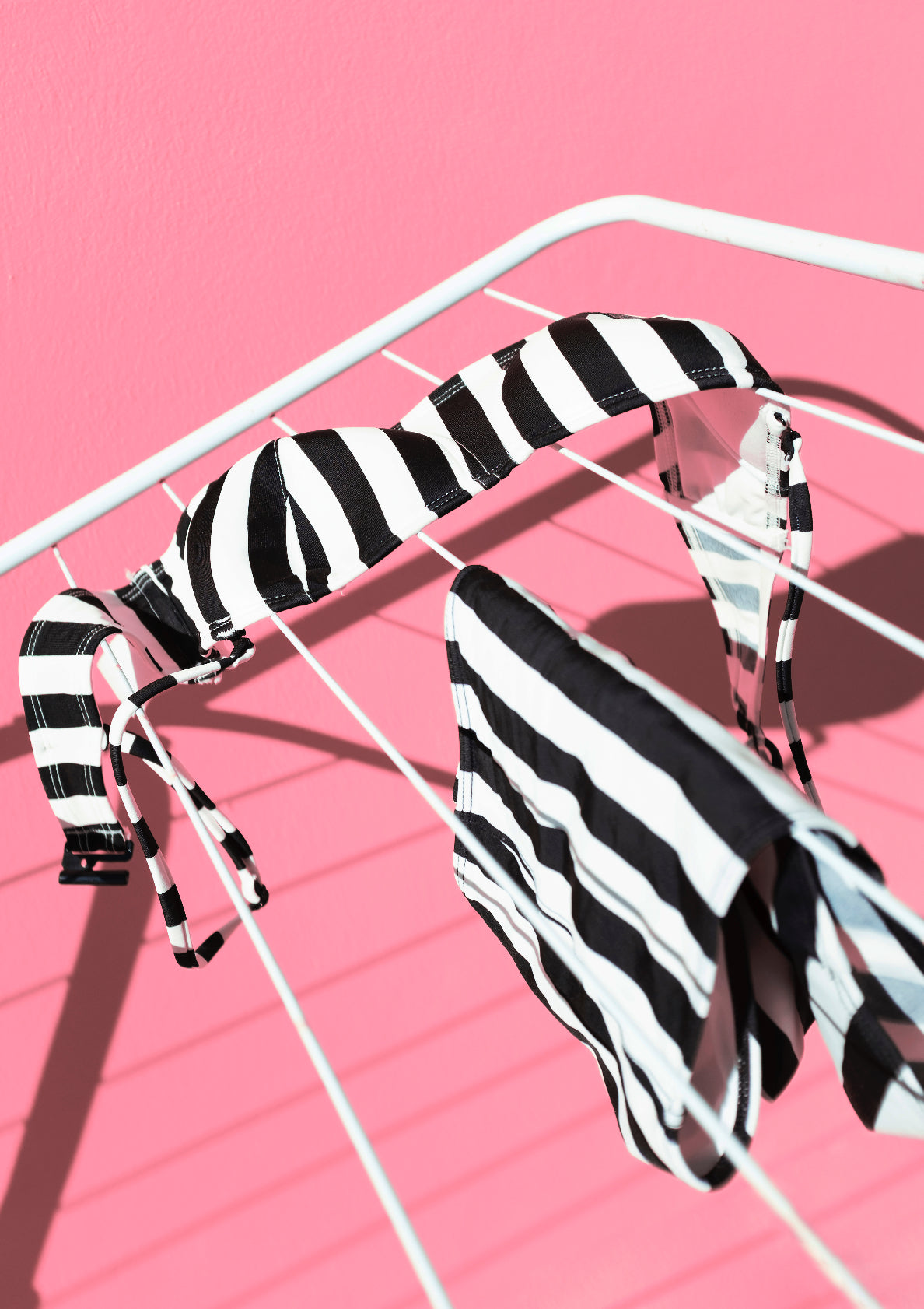 Black-and-white stripe pattern bikini oon a front of pink wall / Pop art style photo print