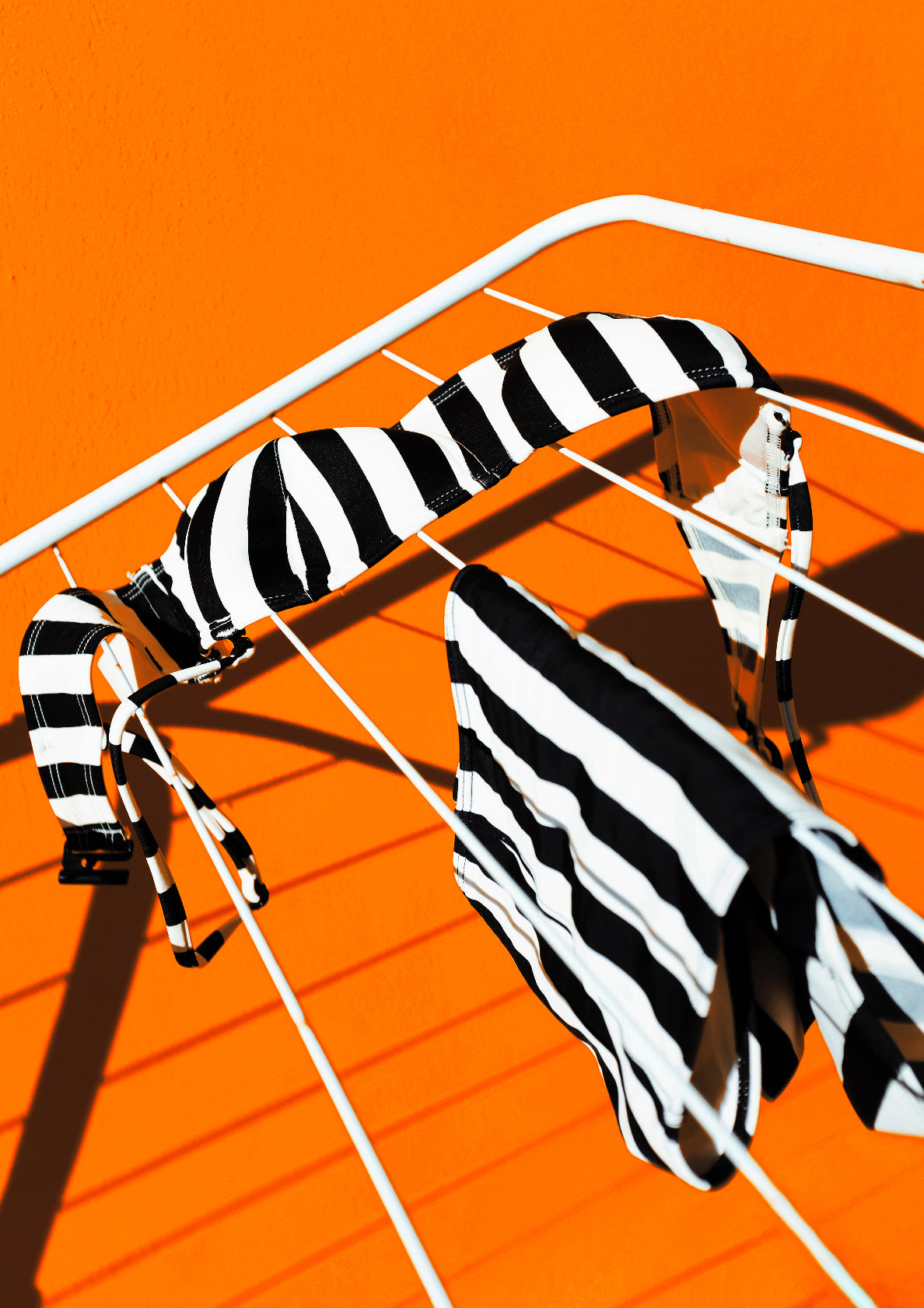 Black-and-white stripe pattern bikini oon a front of orange wall / Pop art style photo print